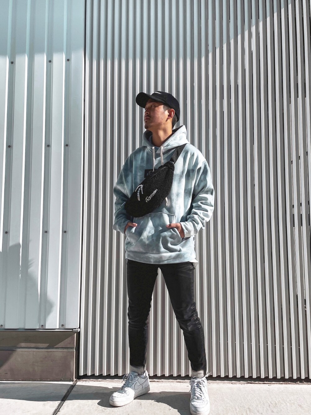 ブルー系のパーカー、ブラック系のボディバッグ/ウエストポーチ、ブラック系のデニムパンツを着用したメンズの冬コーディネートの1枚目の写真