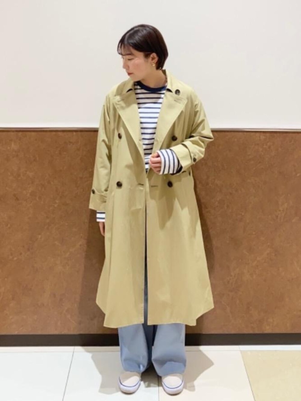 ベージュ系のトレンチコート、ブルー系のその他パンツ、ホワイト系のTシャツ/カットソーを着用したレディースの冬コーディネートの1枚目の写真