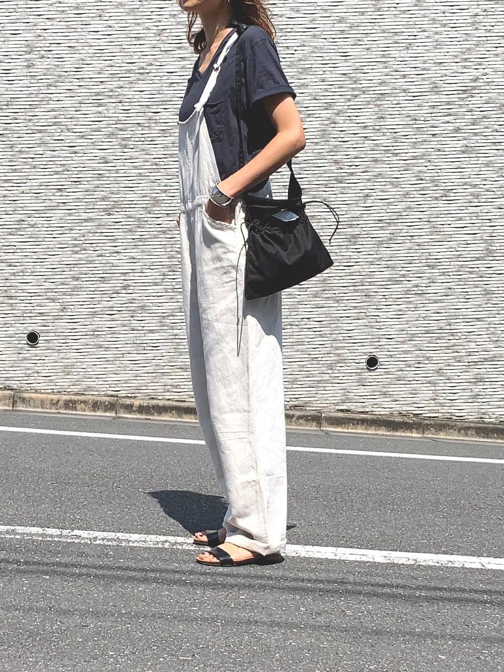 グレー系のTシャツ/カットソー、ブラック系のショルダーバッグ、ブラック系のサンダルを着用したレディースの夏コーディネートの1枚目の写真