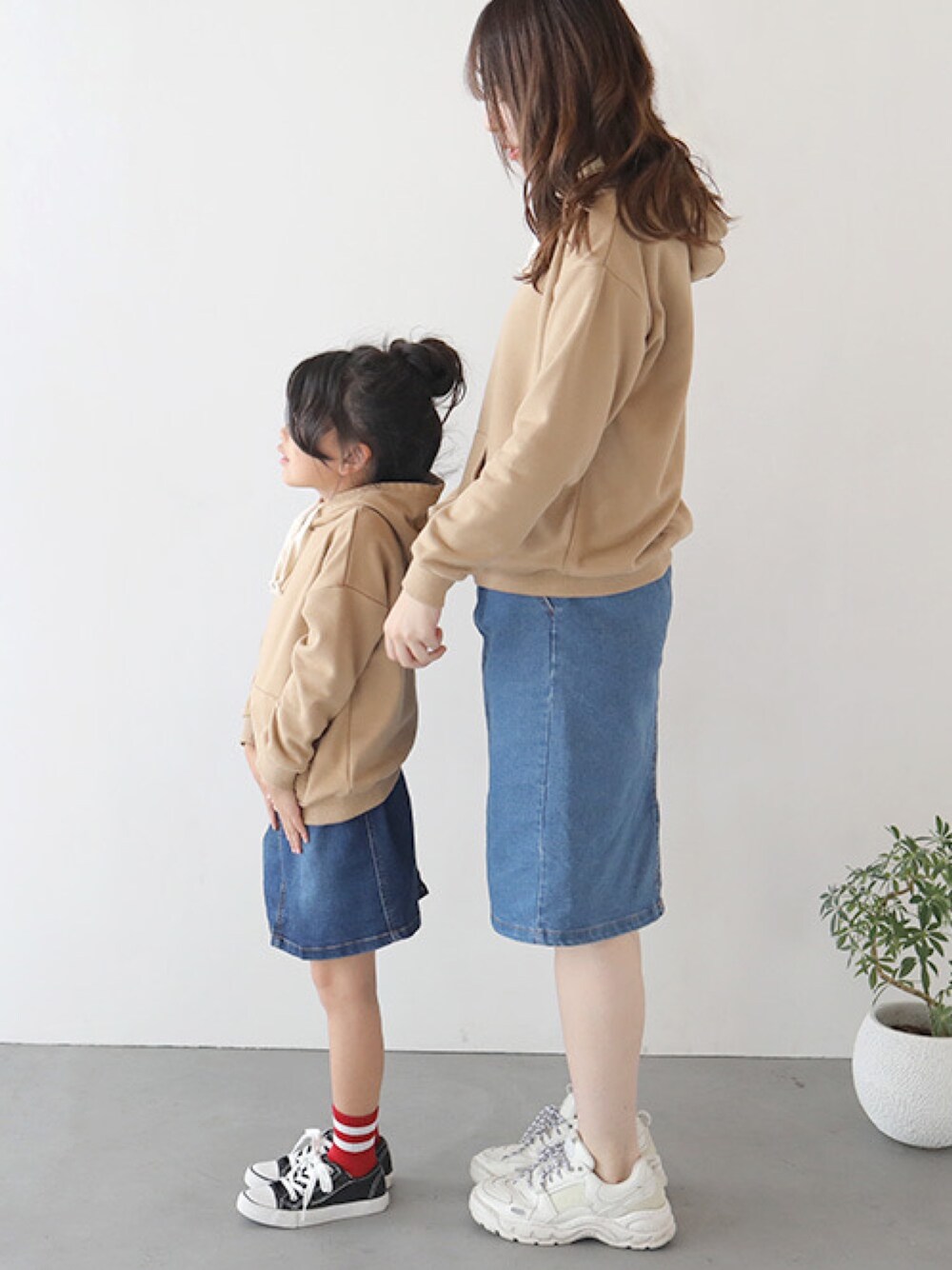 ブラウン系のパーカー、ブルー系のデニムスカート、ホワイト系のその他を着用したキッズの秋コーディネートの1枚目の写真