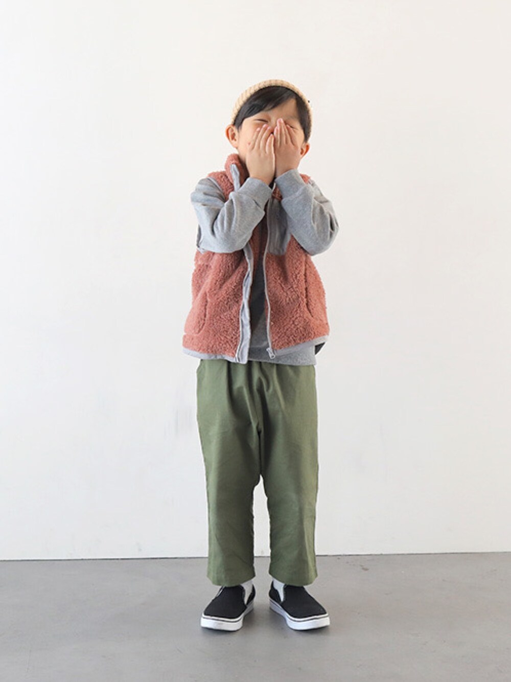 ピンク系のベスト、グレー系のスウェット、グリーン系のその他パンツを着用したキッズの秋コーディネートの1枚目の写真