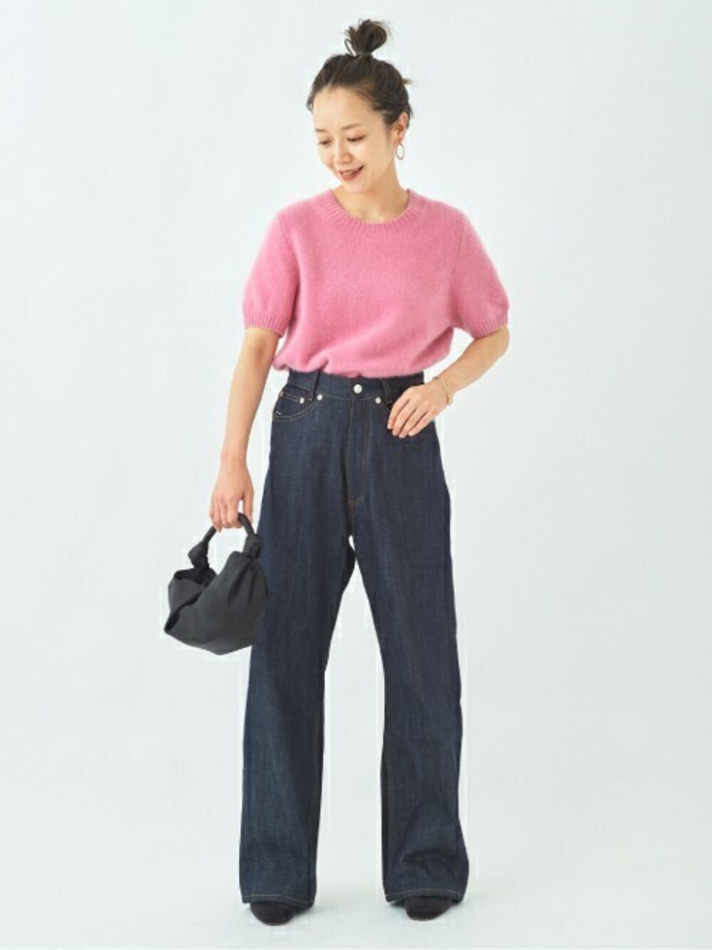 ピンク系のニット/セーター、ブルー系のデニムパンツ、ゴールド系のピアス(両耳用)を着用したレディースの夏コーディネートの1枚目の写真