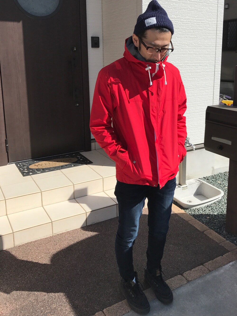 「休日スタイル、デニム、ニット帽、マウンテンパーカー、めがね」｜「JOURNAL STANDARDの【MENS NONNO4月号掲載】FREEMAN / フリーマン: WATERPROOF RAIN JACKET / ナイロンジャケット（ナイロンジャケット、レッド系）」を使った、ハナさん（メンズ・174cm）の冬コーディネートの1枚目の写真