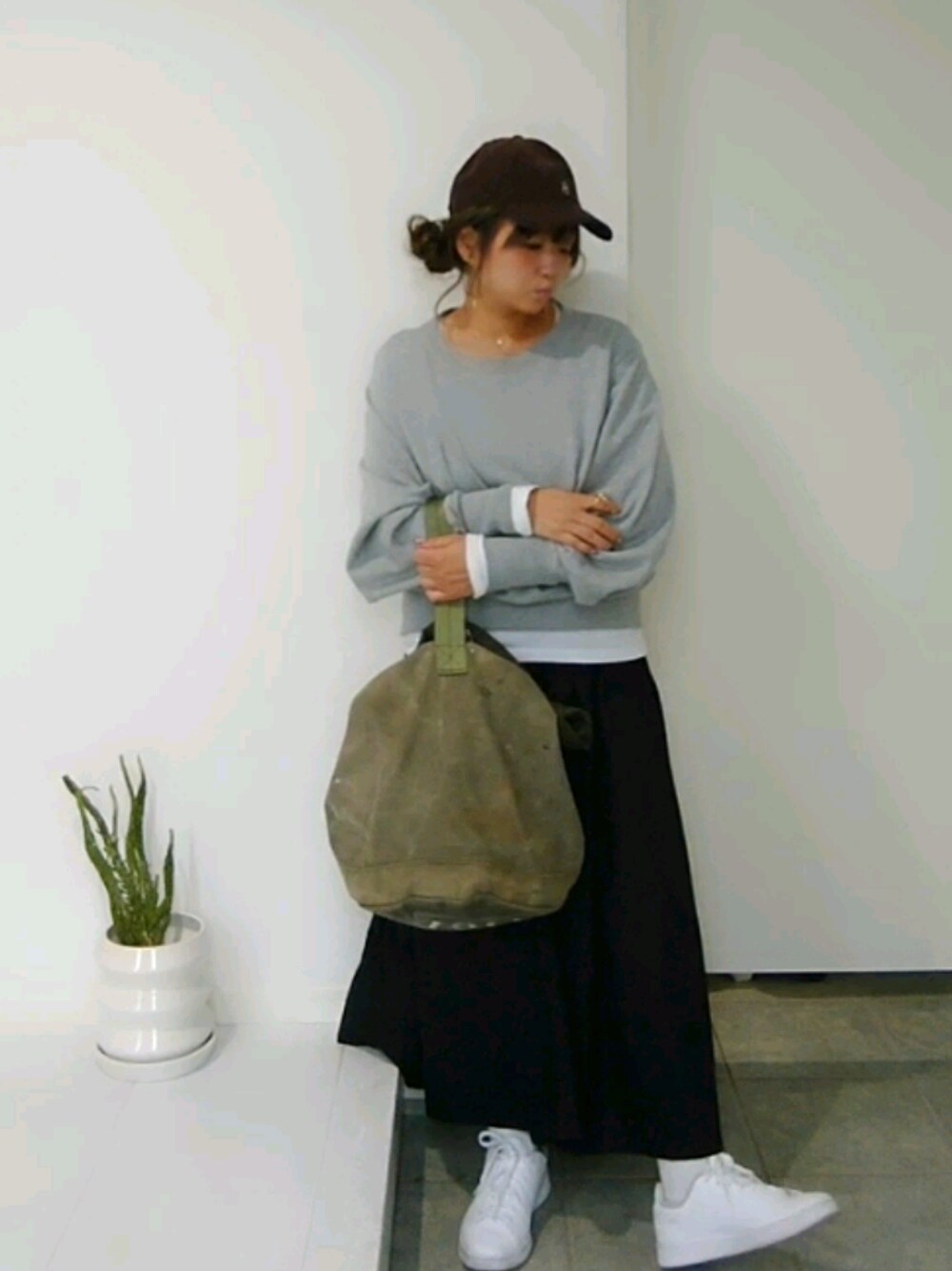 グレー系のスウェット、ブラウン系のキャップを着用したレディースの冬コーディネートの1枚目の写真