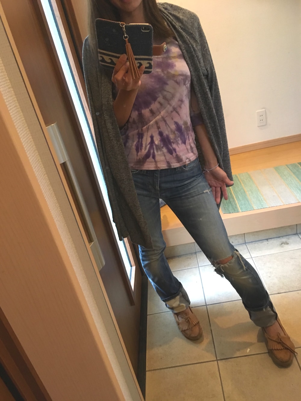 ブルー系のデニムパンツ、パープル系のTシャツ/カットソー、グレー系のカーディガン/ボレロを着用したレディースの秋コーディネートの1枚目の写真