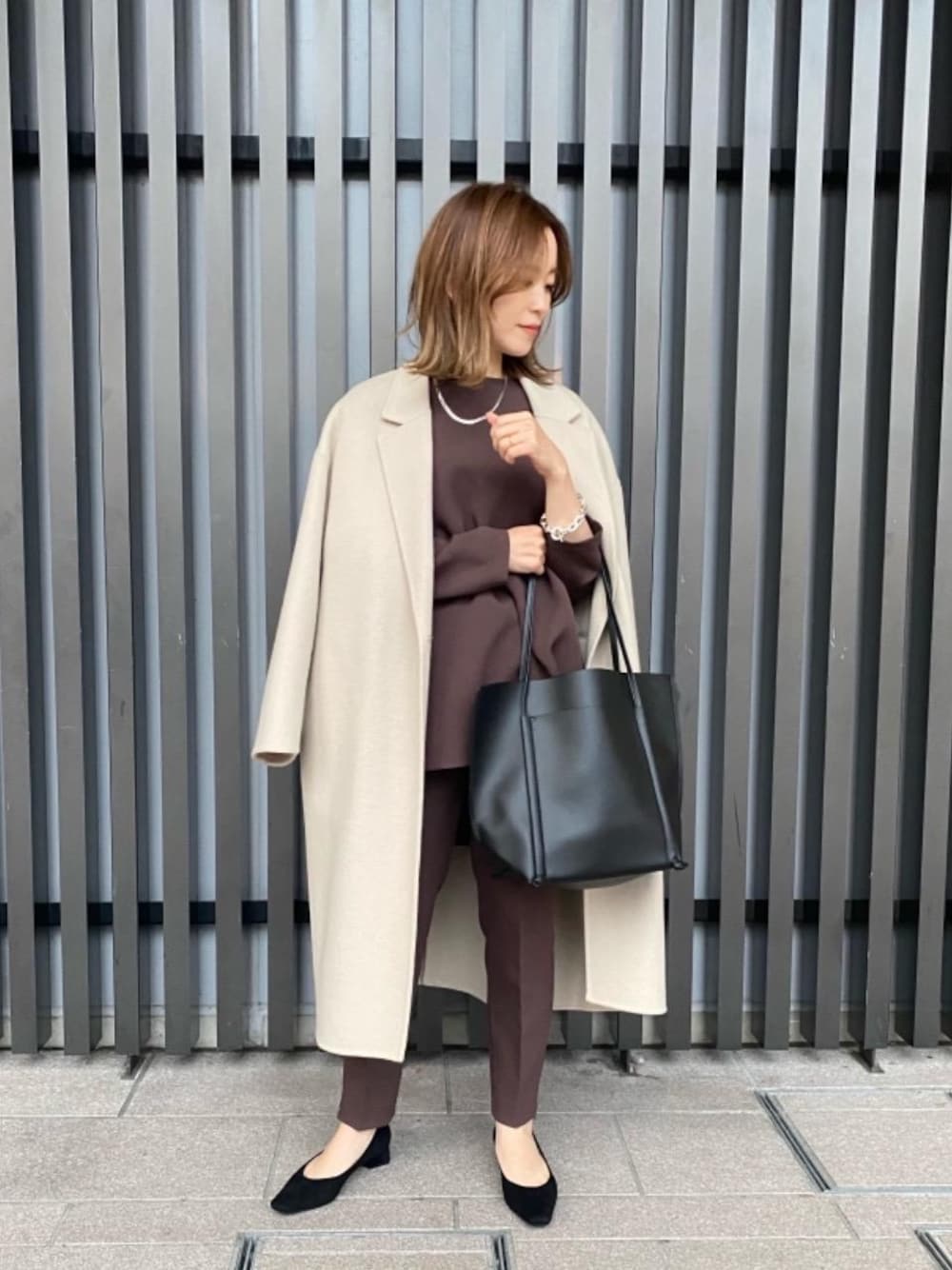 ベージュ系のチェスターコート、ブラウン系のその他パンツ、ブラック系のトートバッグを着用したレディースの秋コーディネートの1枚目の写真