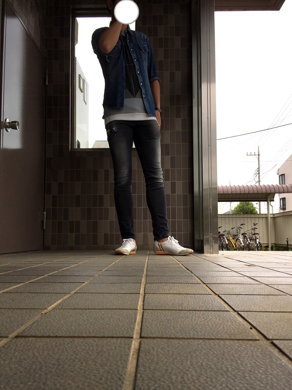 ブラック系のデニムパンツ、ブルー系のシャツ/ブラウス、ホワイト系のスニーカーを着用したメンズの春コーディネートの1枚目の写真