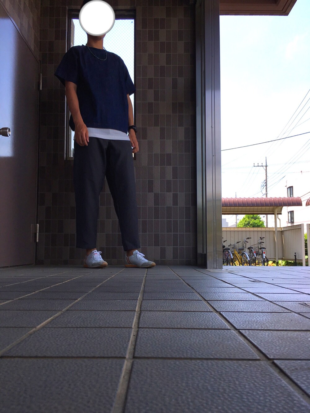 ホワイト系のタンクトップ、グレー系のスラックス、ホワイト系のスニーカーを着用したメンズの春コーディネートの1枚目の写真