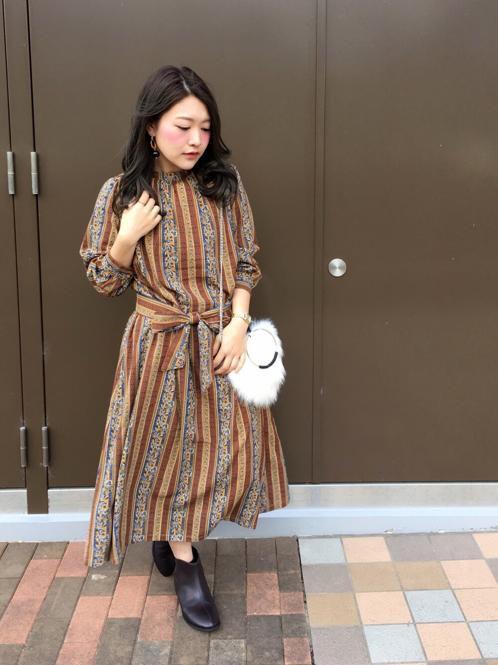 ホワイト系のハンドバッグ、イエロー系のワンピース/ドレス、ブラウン系のブーツを着用したレディースの冬コーディネートの1枚目の写真