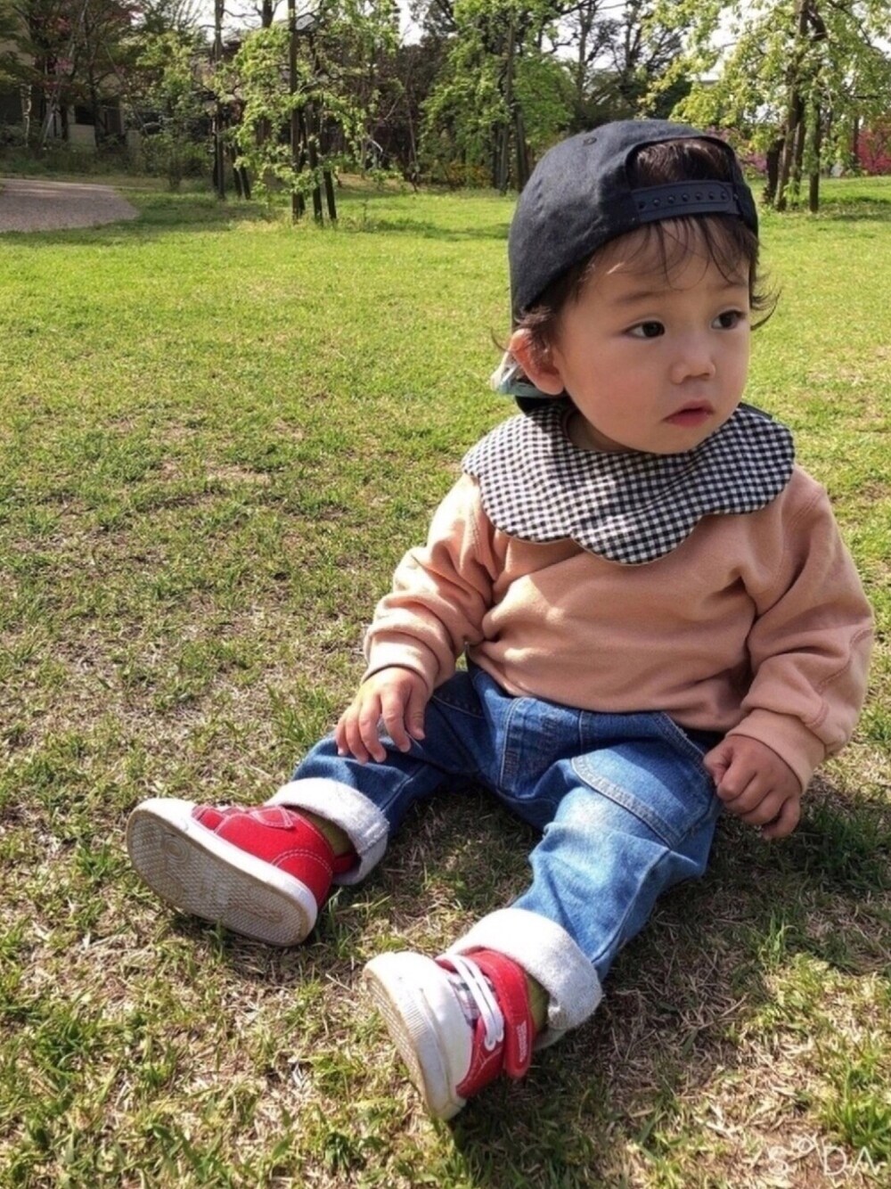 オレンジ系のスウェット、ブルー系のデニムパンツ、ブラック系のキャップを着用したキッズの春コーディネートの1枚目の写真