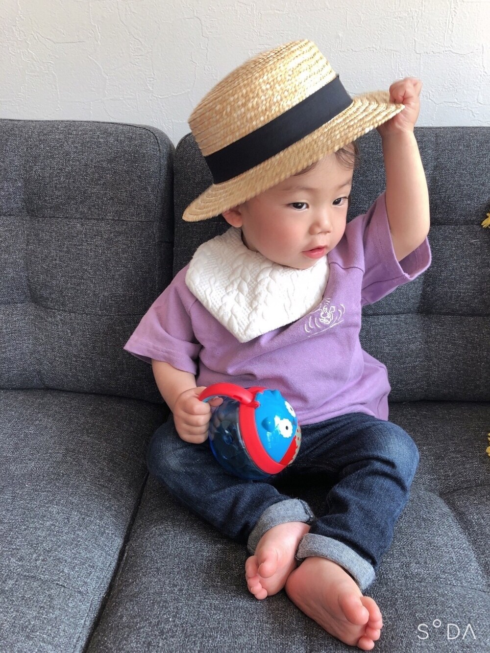 パープル系のTシャツ/カットソー、ブルー系のデニムパンツ、ベージュ系の帽子を着用したキッズの春コーディネートの1枚目の写真