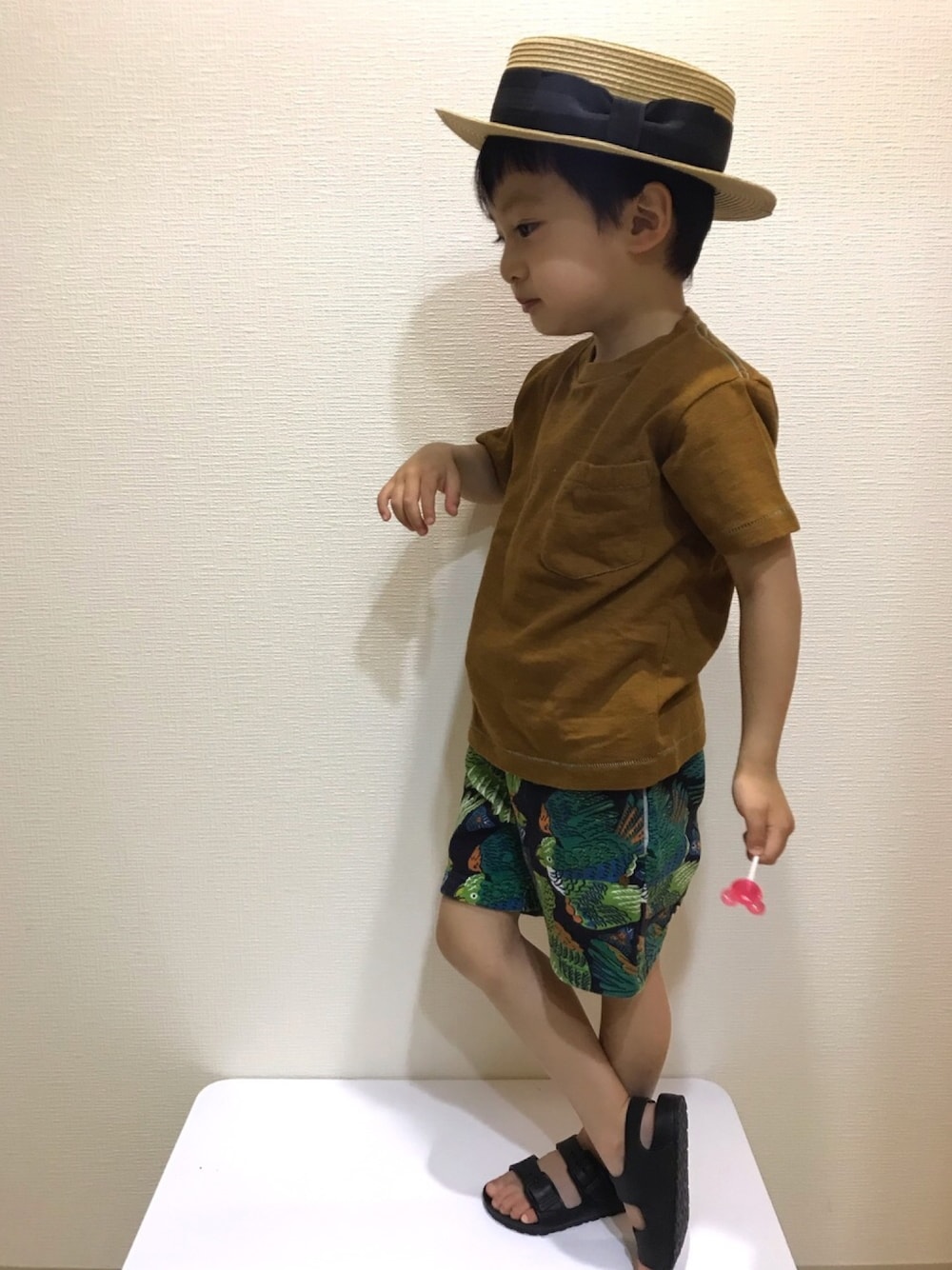 ブラウン系のTシャツ/カットソー、ブラック系のパンツ、ブラック系のサンダルを着用したキッズの夏コーディネートの1枚目の写真