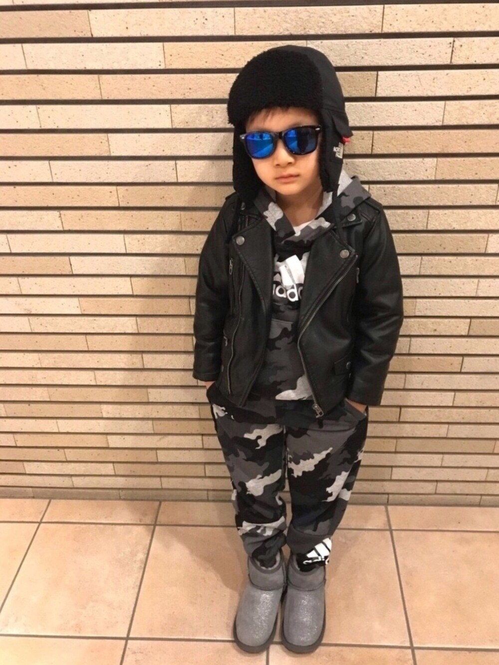ブラック系のライダースジャケット、グレー系のパーカー、グレー系のブーツを着用したキッズの秋コーディネートの1枚目の写真