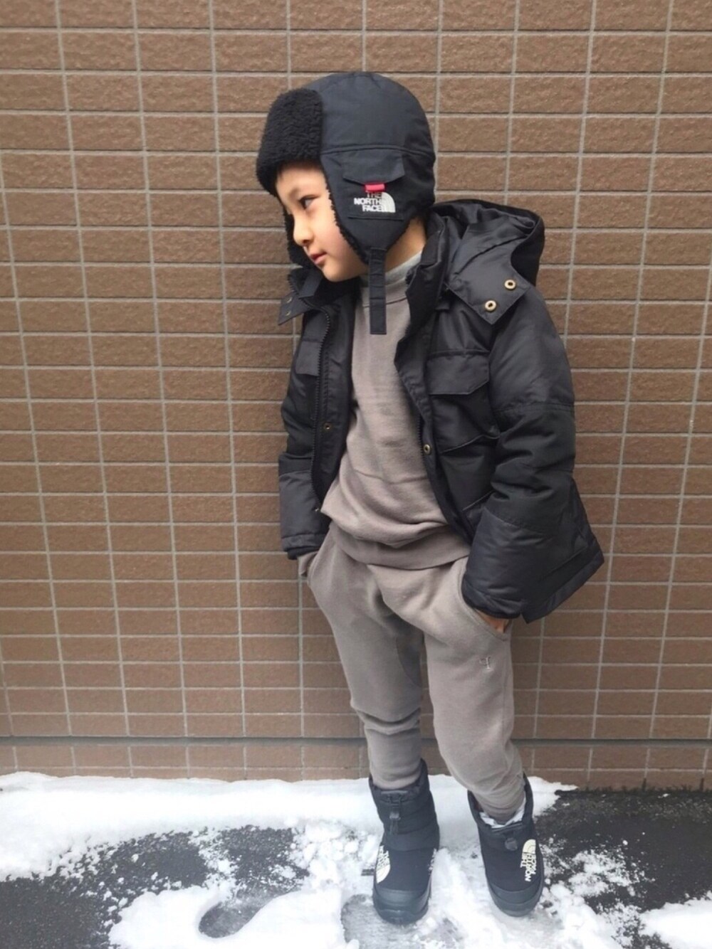 ブラック系のダウンジャケット/コート、グレー系のスウェット、グレー系のTシャツ/カットソーを着用したキッズの冬コーディネートの1枚目の写真