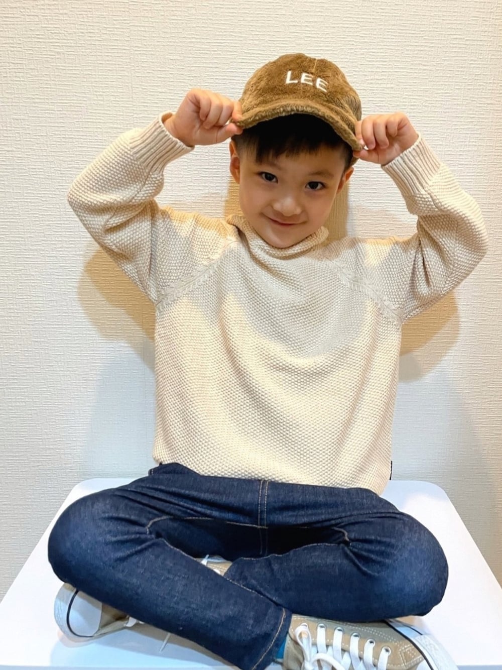 ホワイト系のニット/セーター、ブルー系のデニムパンツ、ベージュ系のスニーカーを着用したキッズの冬コーディネートの1枚目の写真