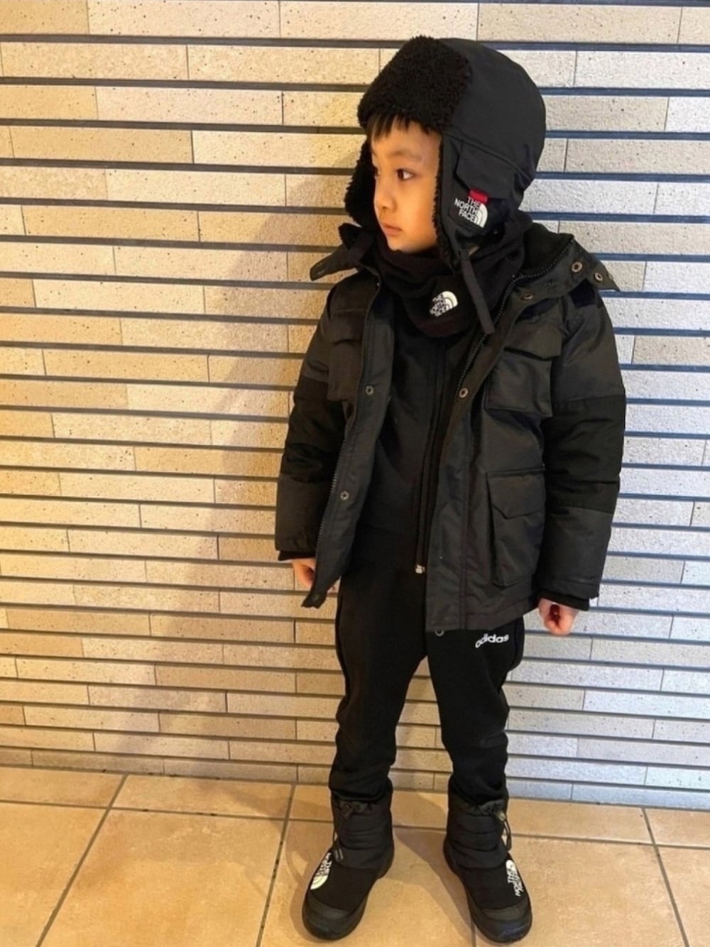 ブラック系のダウンジャケット/コート、ブラック系のジャージ、ブラック系のブーツを着用したキッズの冬コーディネートの1枚目の写真