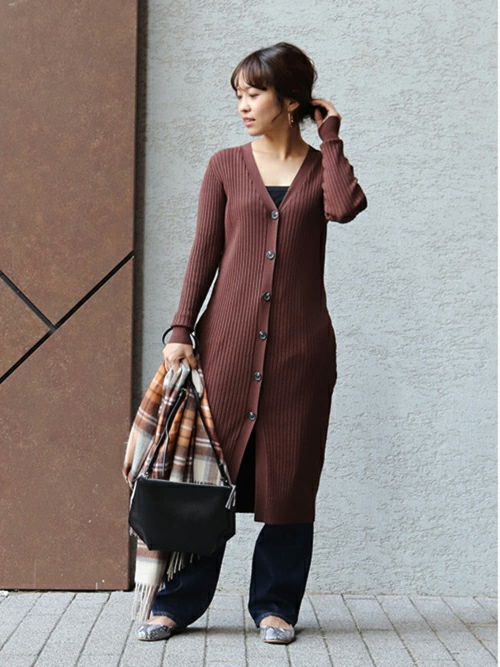 ブラウン系のカーディガン/ボレロ、ブラック系のショルダーバッグ、ブルー系のデニムパンツを着用したレディースの冬コーディネートの1枚目の写真