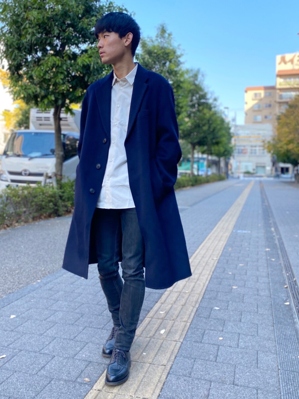 ブラック系のデニムパンツ、ブルー系のチェスターコート、ホワイト系のシャツ/ブラウスを着用したメンズの秋コーディネートの1枚目の写真