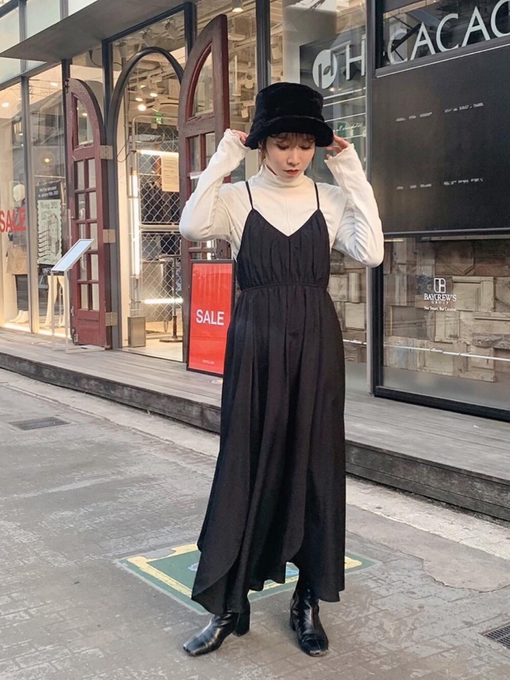 ブラック系のワンピース、ブラック系のブーツを着用したレディースの冬コーディネートの1枚目の写真