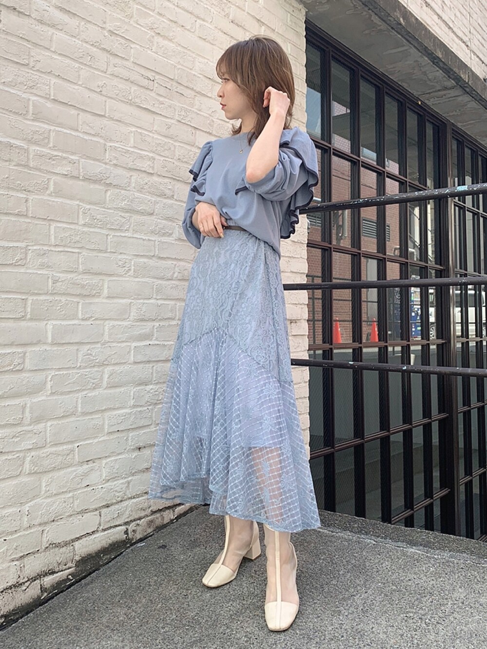 ブルー系のニット/セーター、ブルー系のスカート、ホワイト系のブーツを着用したレディースの春コーディネートの1枚目の写真