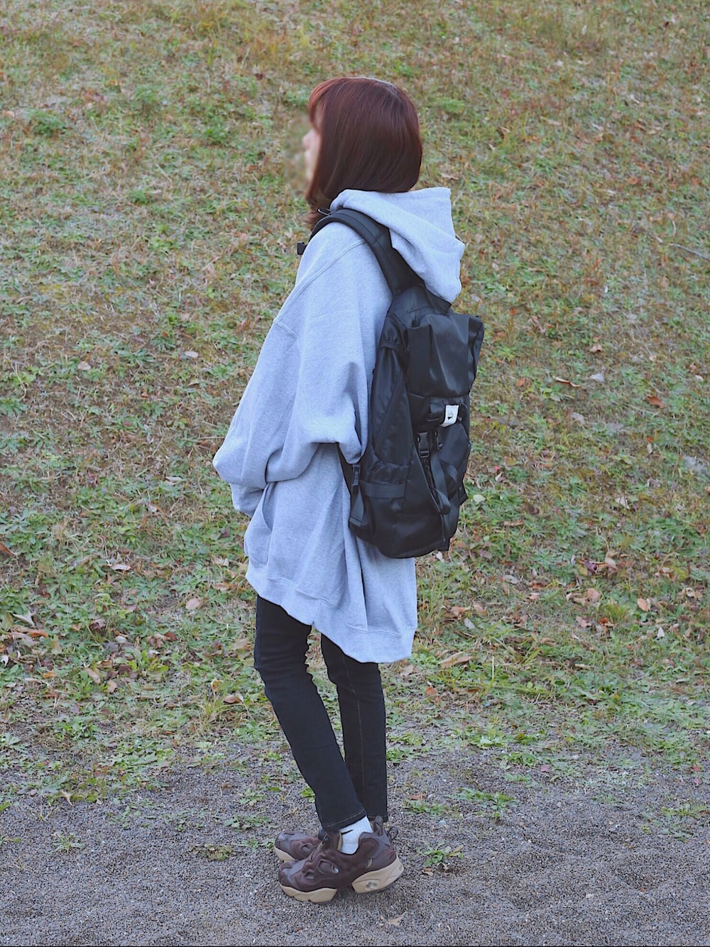 グレー系のパーカー、ブラック系のデニムパンツ、ブラック系のバックパック/リュックを着用したレディースの冬コーディネートの1枚目の写真