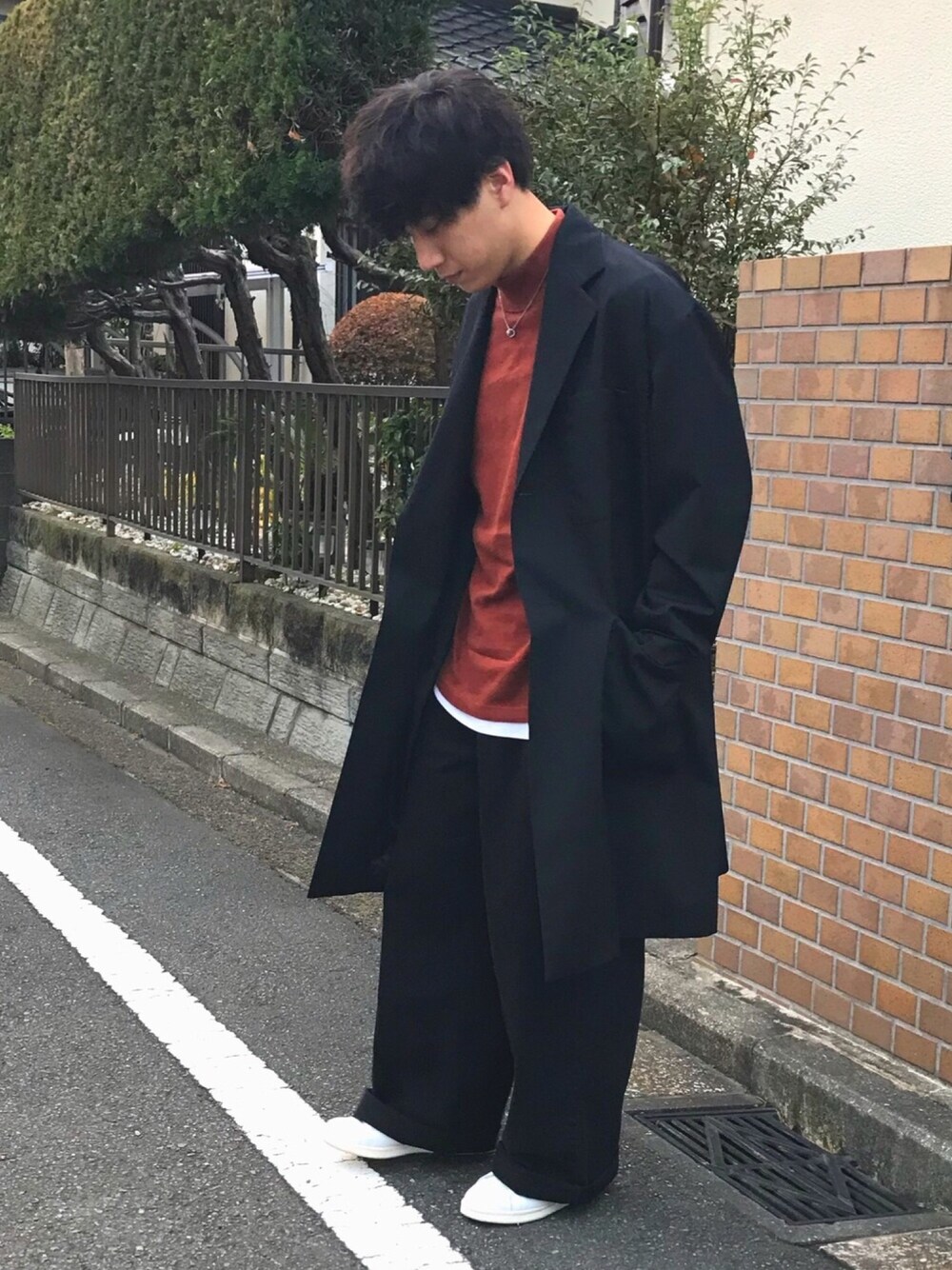 ブラック系のチェスターコート、ブラウン系のTシャツ/カットソー、ホワイト系のTシャツ/カットソーを着用したメンズの秋コーディネートの1枚目の写真