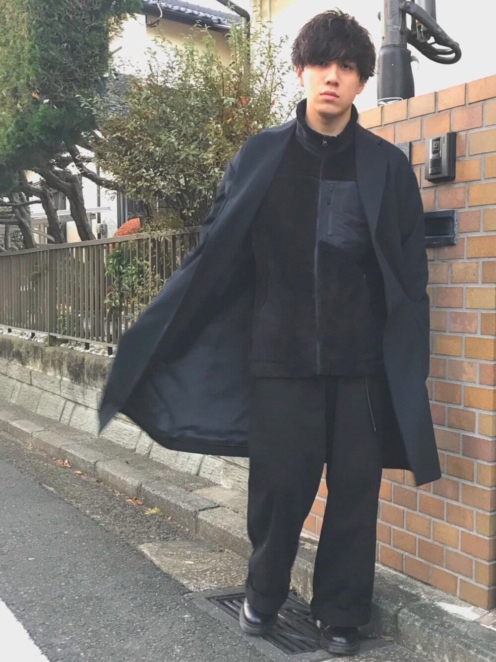 ブラック系のチェスターコート、ブラック系のその他アウター、ブラック系のデニムパンツを着用したメンズの冬コーディネートの1枚目の写真