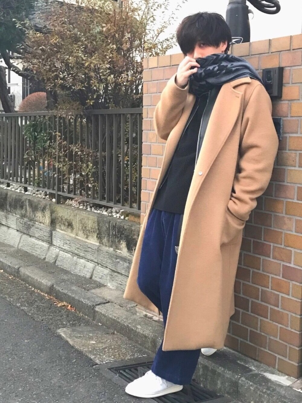 イエロー系のチェスターコート、ブラック系のニット/セーター、ブルー系のその他パンツを着用したメンズの冬コーディネートの1枚目の写真
