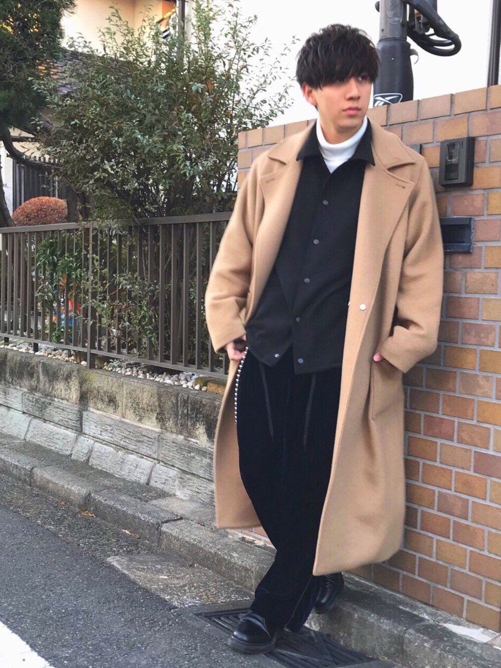 イエロー系のチェスターコート、ブラック系のブルゾン、ホワイト系のTシャツ/カットソーを着用したメンズの冬コーディネートの1枚目の写真