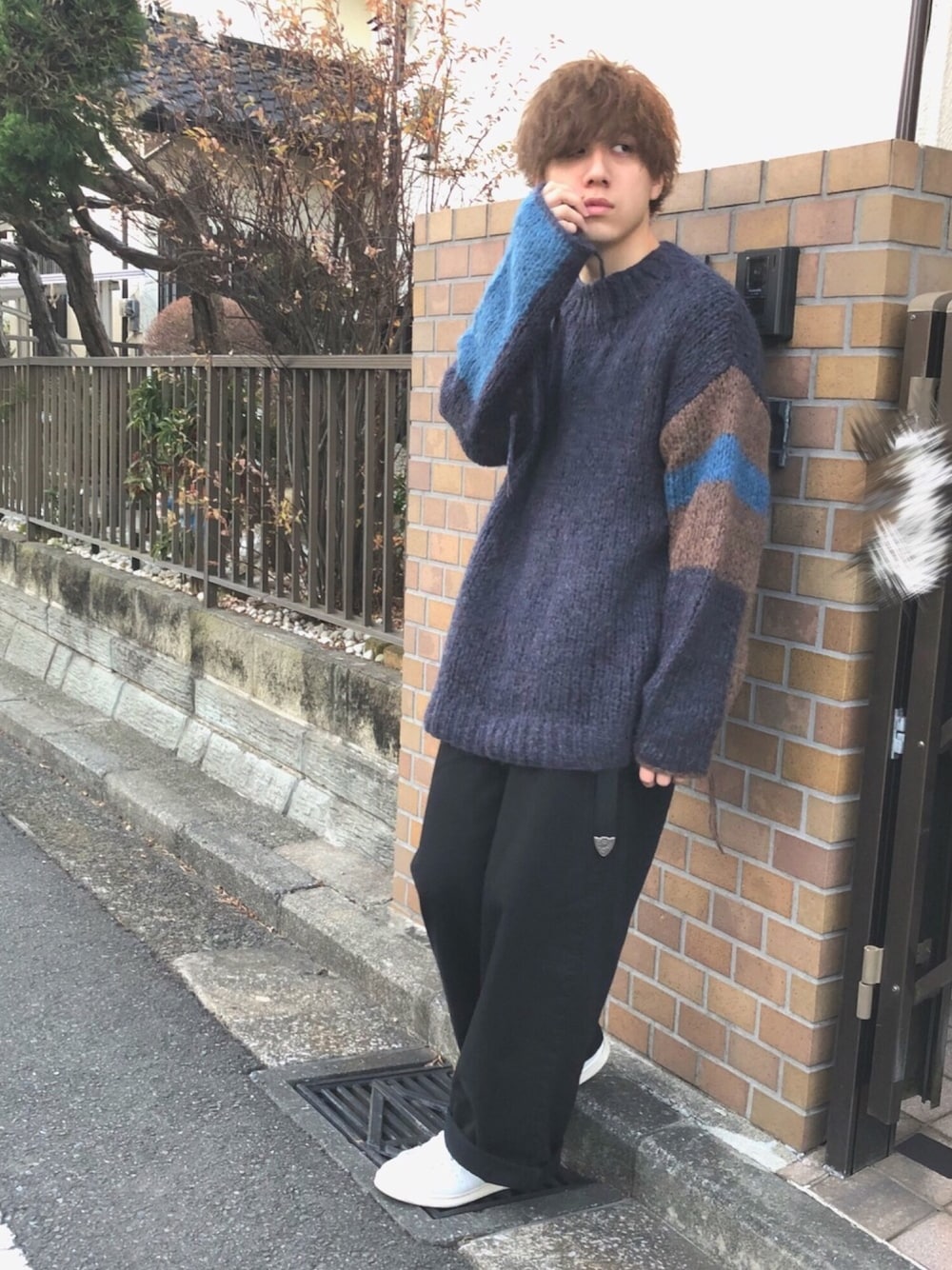 ブルー系のニット/セーター、ブラック系のデニムパンツ、ホワイト系のスニーカーを着用したメンズの冬コーディネートの1枚目の写真