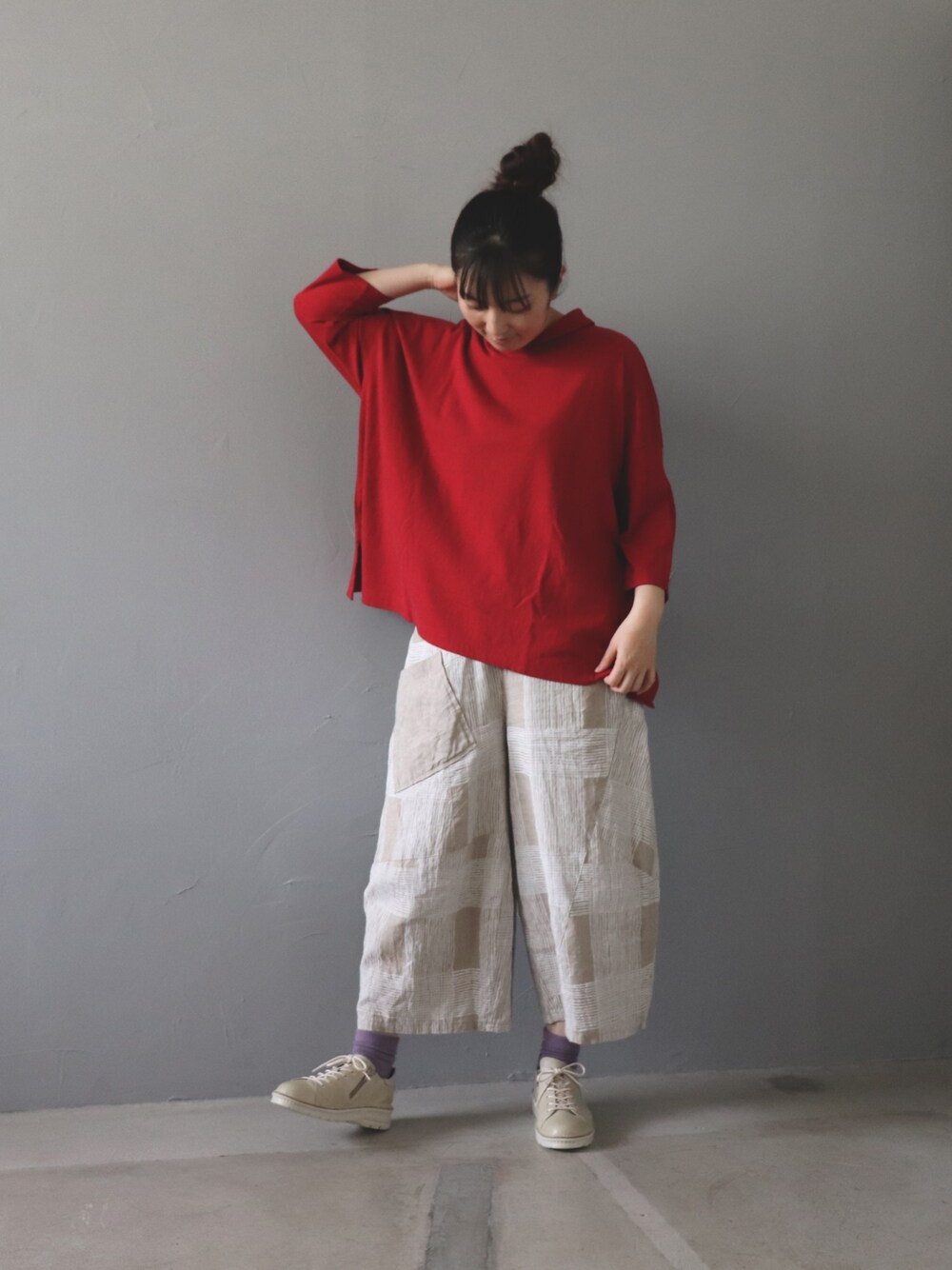 レッド系のトップス、ベージュ系のパンツ、ホワイト系のシューズを着用したレディースの春コーディネートの1枚目の写真