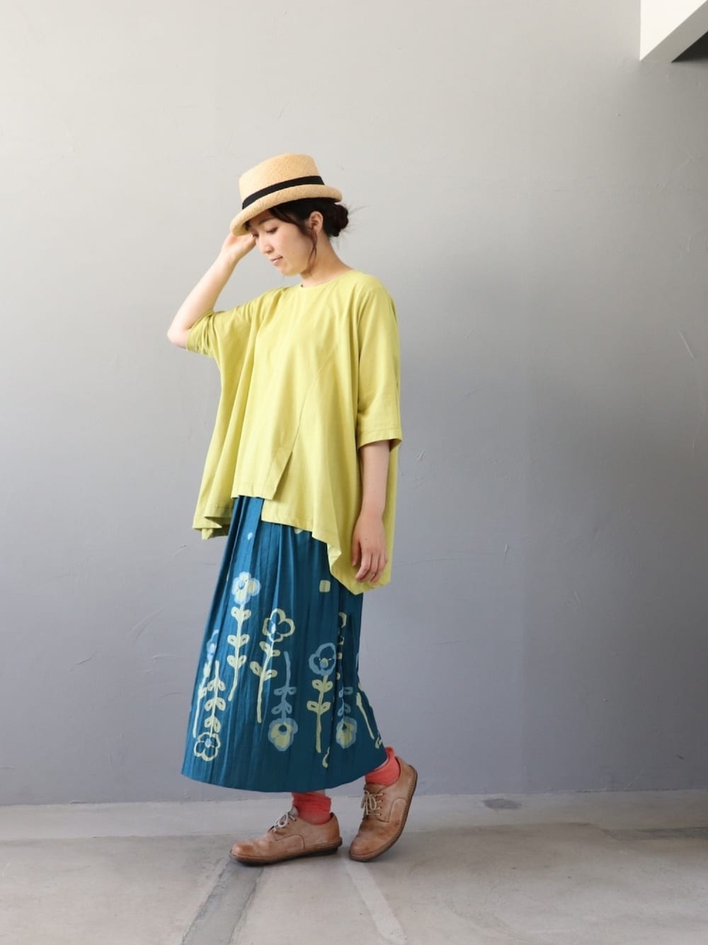 イエロー系のトップス、ブルー系のスカート、ベージュ系のシューズを着用したレディースの夏コーディネートの1枚目の写真