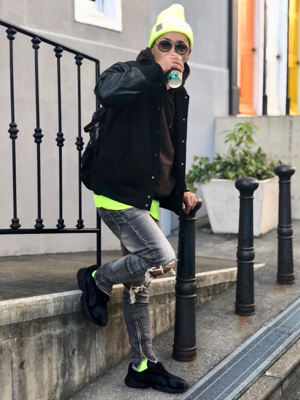 ブラック系のスタジャン、ブラウン系のパーカー、イエロー系のタンクトップを着用したメンズの秋コーディネートの1枚目の写真