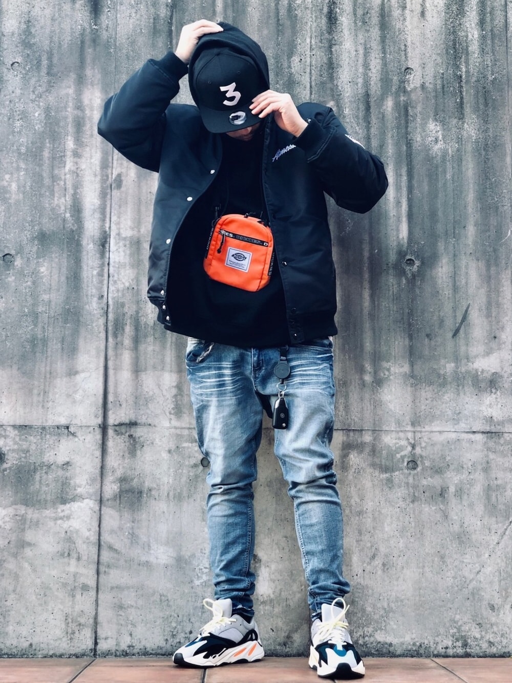 ブラック系のその他アウター、ブラック系のパーカー、ブルー系のデニムパンツを着用したメンズの冬コーディネートの1枚目の写真