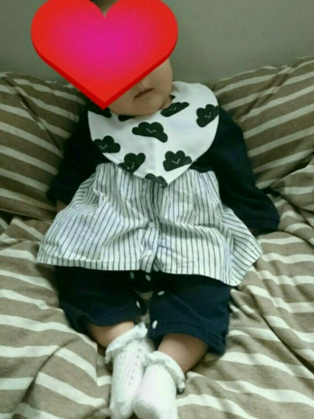 ホワイト系のスタイ/よだれかけ、ブラック系のロンパース、ホワイト系のソックス/靴下を着用したキッズの春コーディネートの1枚目の写真