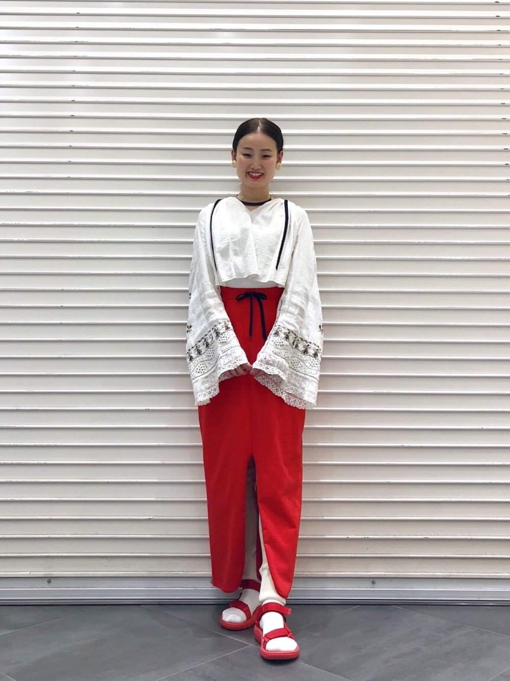 レッド系のスカート、レッド系のサンダル、ブラック系のネックレスを着用したレディースの春コーディネートの1枚目の写真