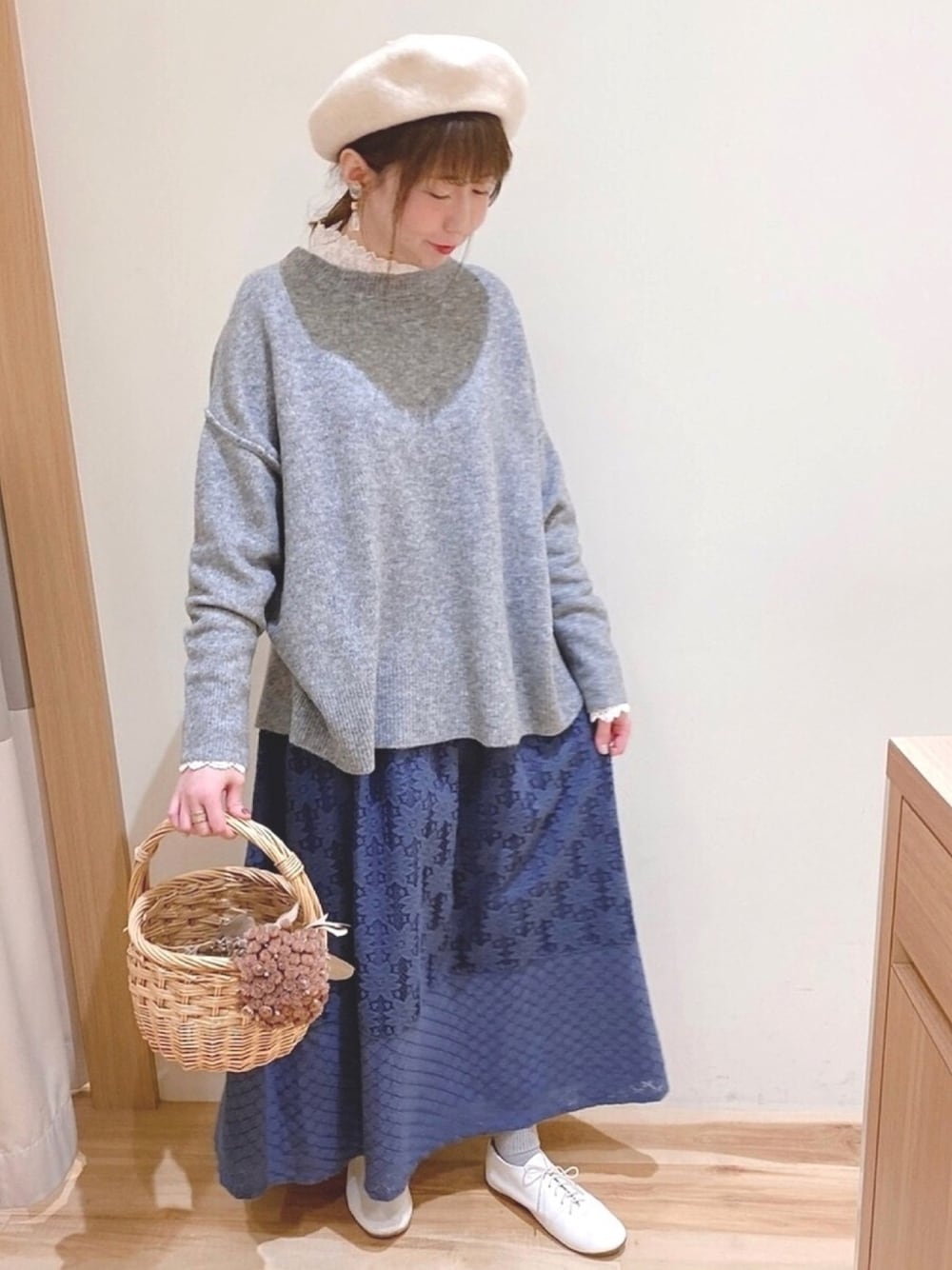 グレー系のニット/セーター、ブルー系のスカートを着用したレディースの秋コーディネートの1枚目の写真