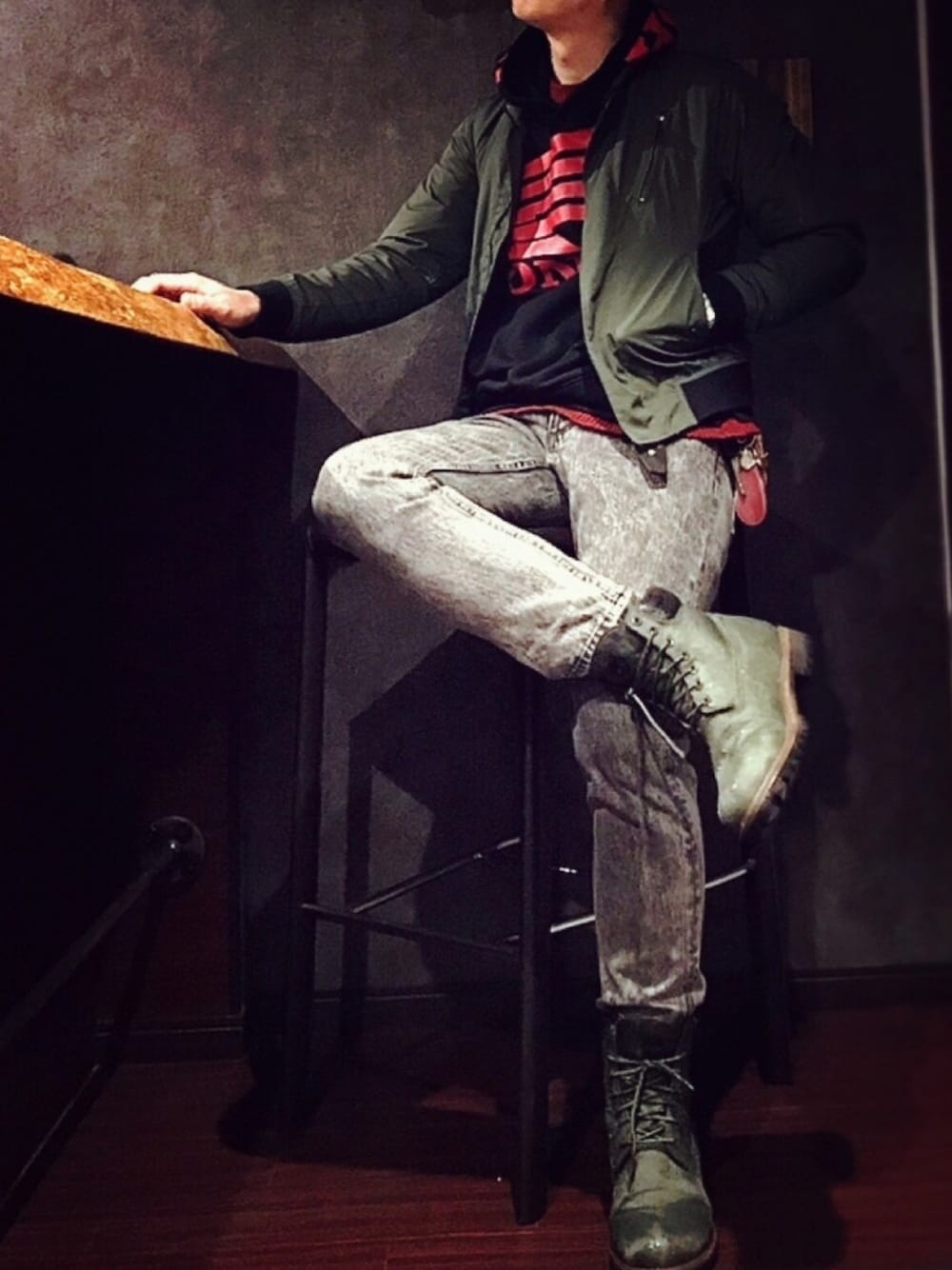 グレー系のデニムパンツ、グリーン系のブーツ、グリーン系のブルゾンを着用したメンズの秋コーディネートの1枚目の写真