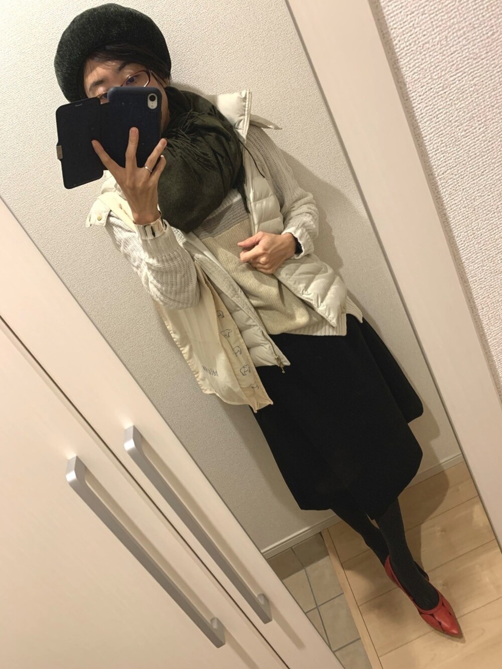 ベージュ系のダウンベスト、ブラック系のスカート、レッド系のパンプスを着用したレディースの冬コーディネートの1枚目の写真
