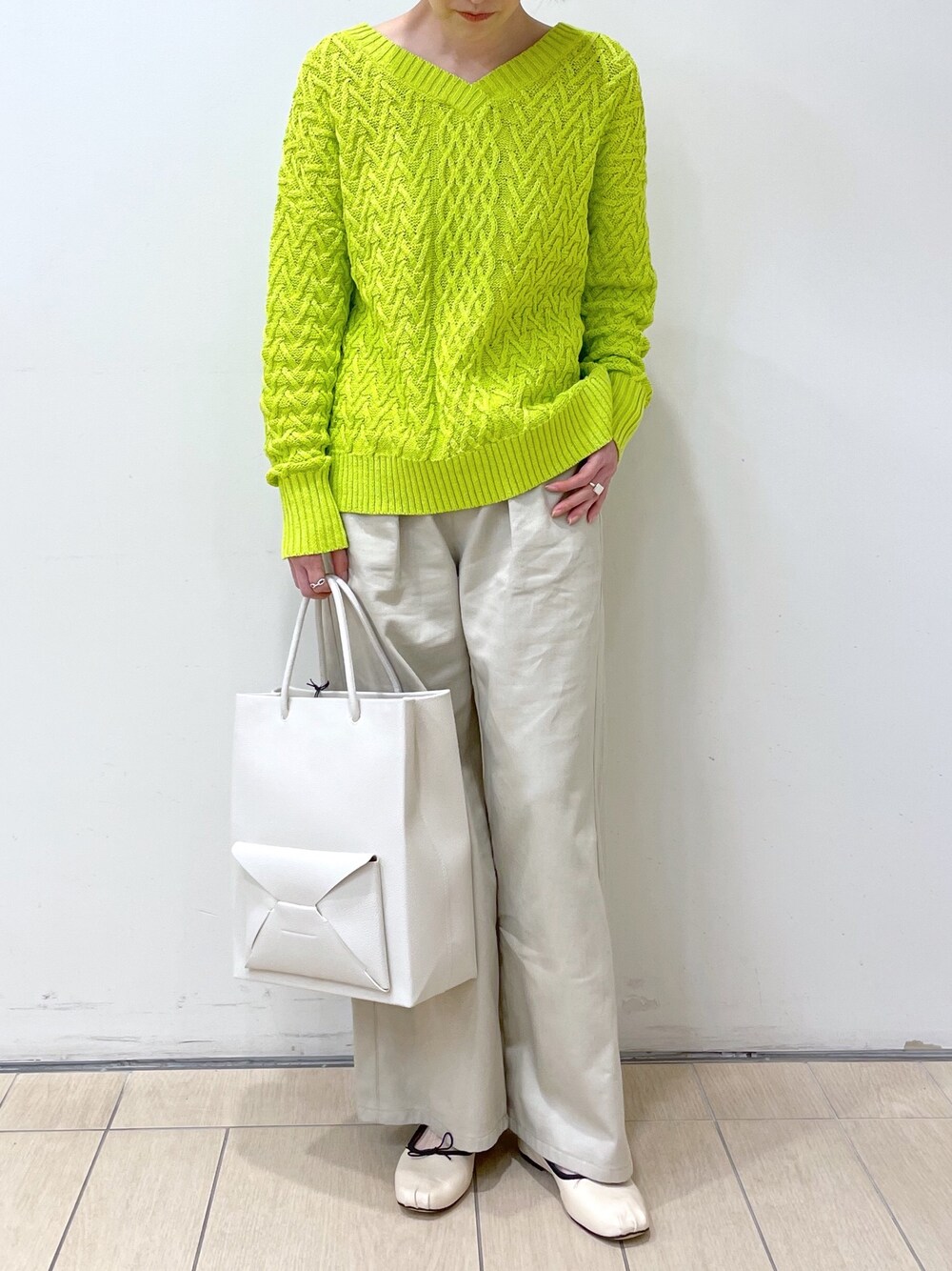 グリーン系のニット/セーター、ベージュ系のその他パンツ、ホワイト系のショルダーバッグを着用したレディースの冬コーディネートの1枚目の写真