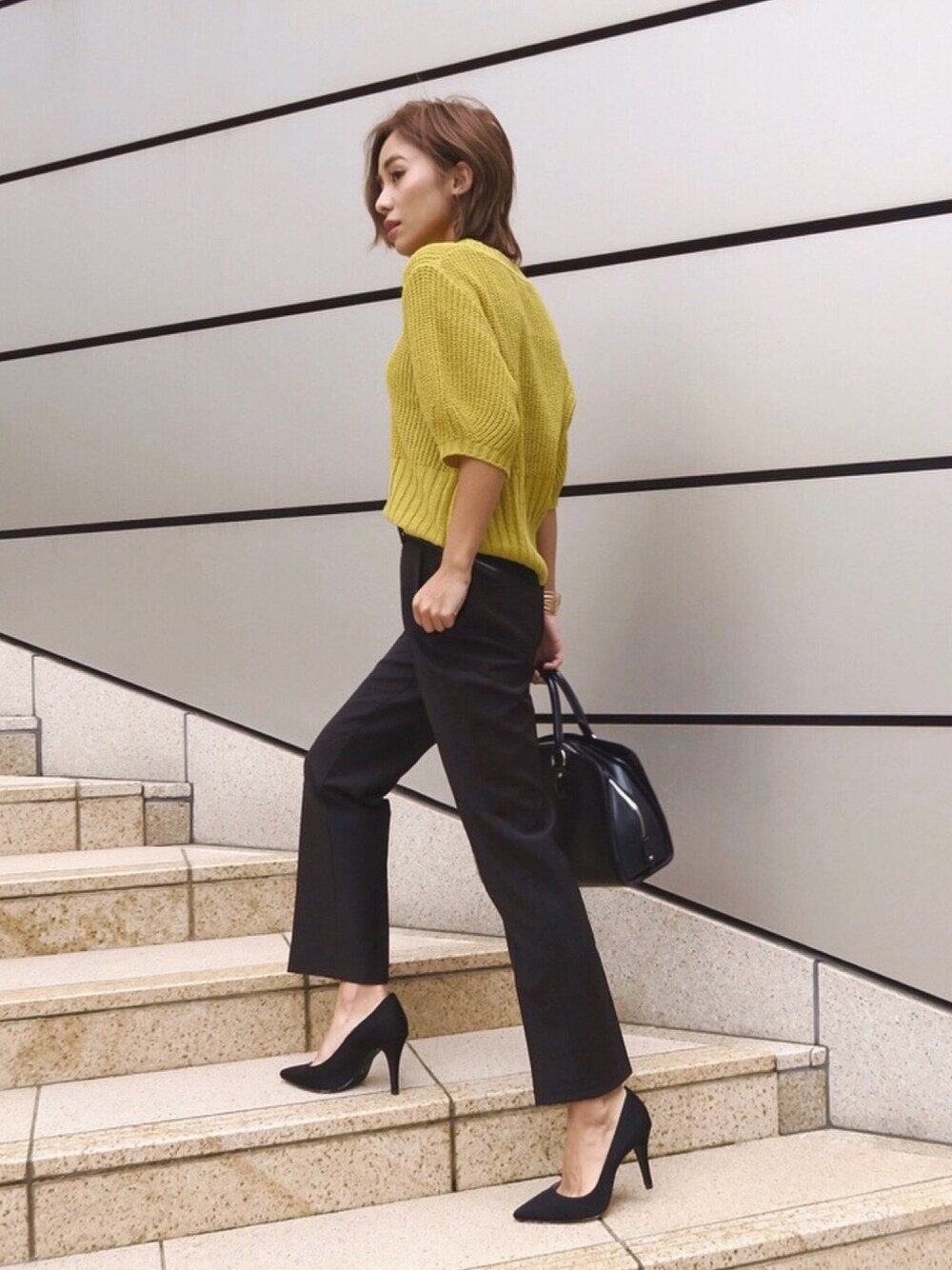 ブラック系のスラックス、イエロー系のTシャツ/カットソーを着用したレディースの秋コーディネートの1枚目の写真