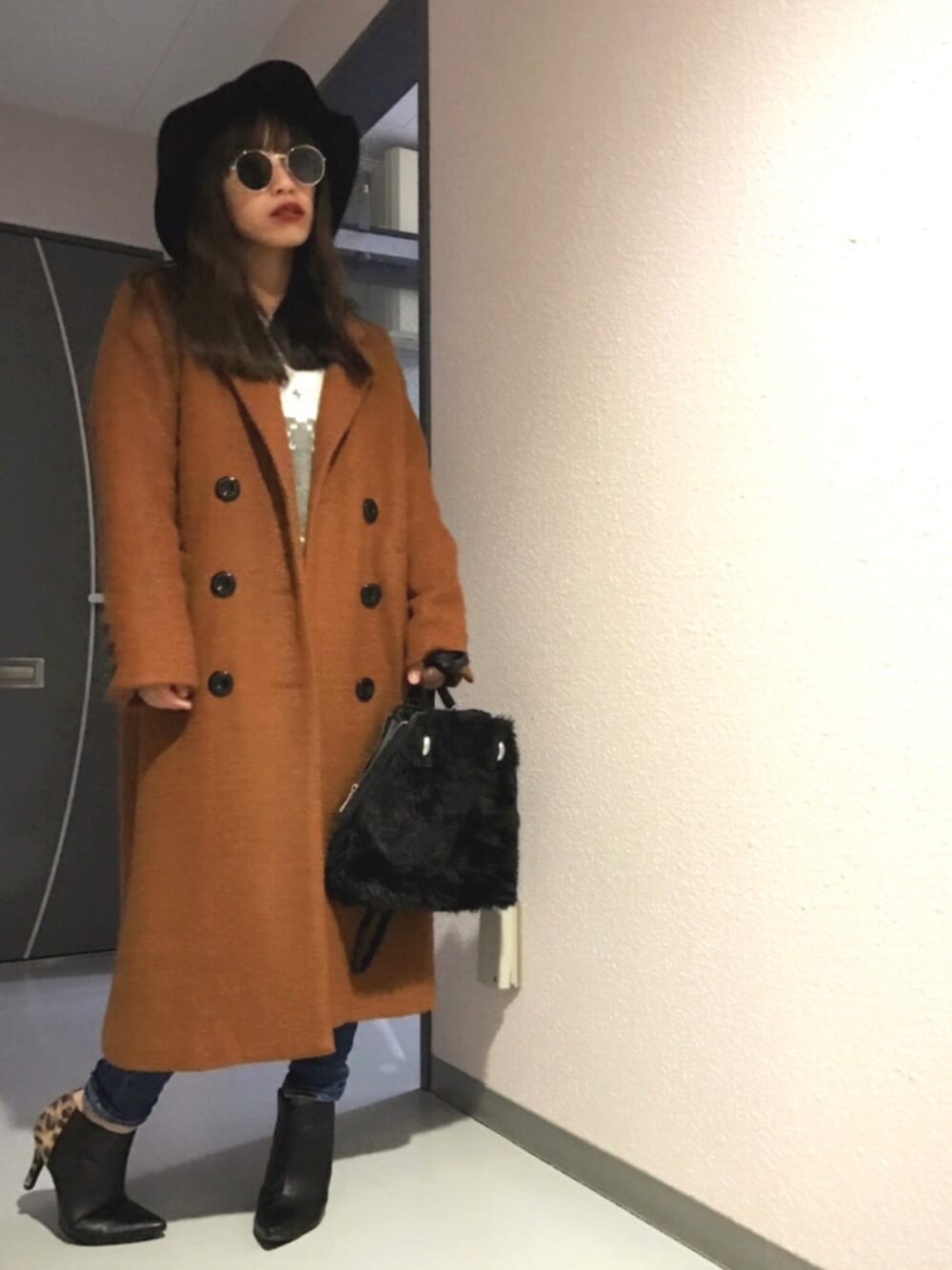 グレー系のニット/セーター、ブラウン系のチェスターコート、ブルー系のデニムパンツを着用したレディースの冬コーディネートの1枚目の写真