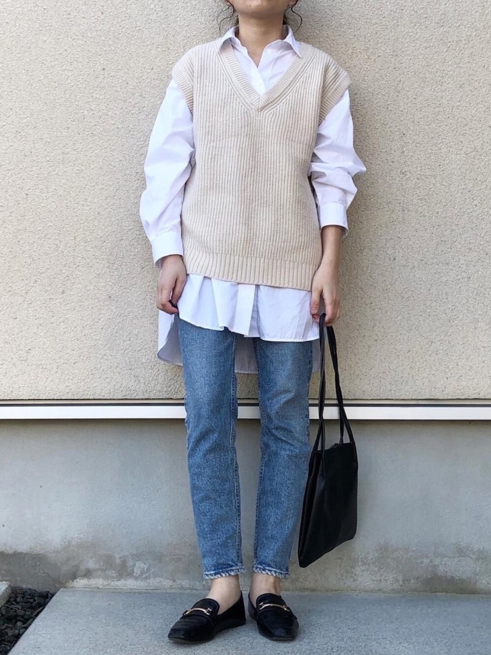 ベージュ系のベスト、ホワイト系のシャツ/ブラウス、ブルー系のデニムパンツを着用したレディースの春コーディネートの1枚目の写真