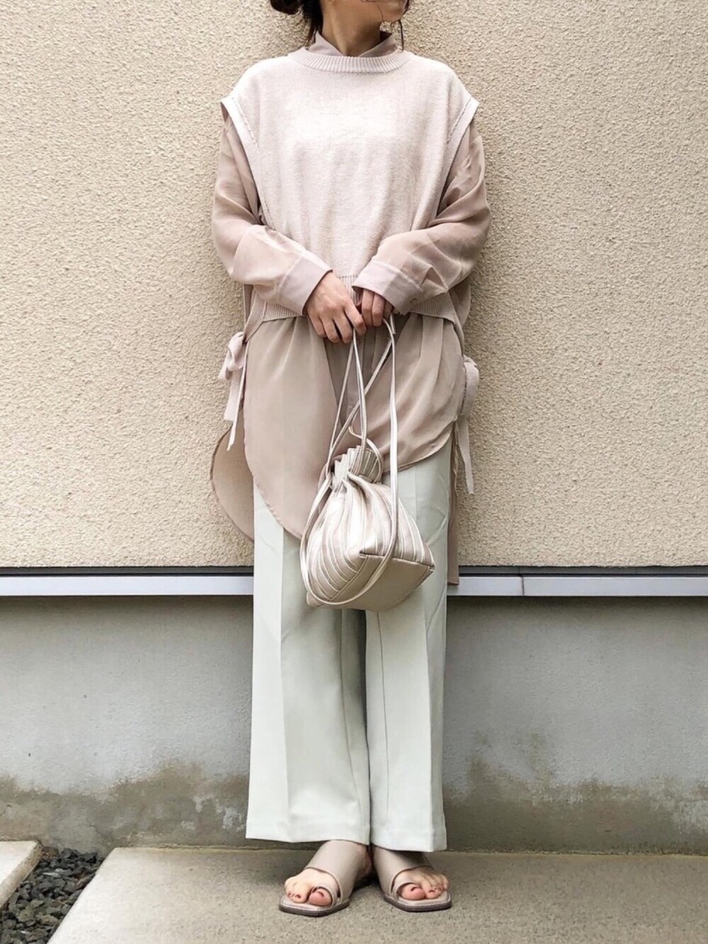 ホワイト系のベスト、ベージュ系のシャツ/ブラウス、ベージュ系のサンダルを着用したレディースの春コーディネートの1枚目の写真