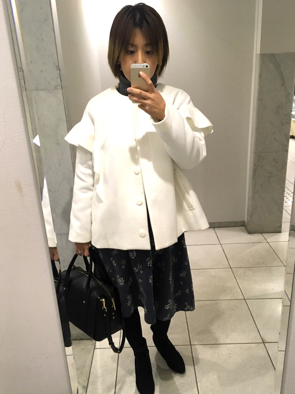 ホワイト系のダウンジャケット/コート、ブラック系のワンピース、ブラック系のハンドバッグを着用したレディースの冬コーディネートの1枚目の写真