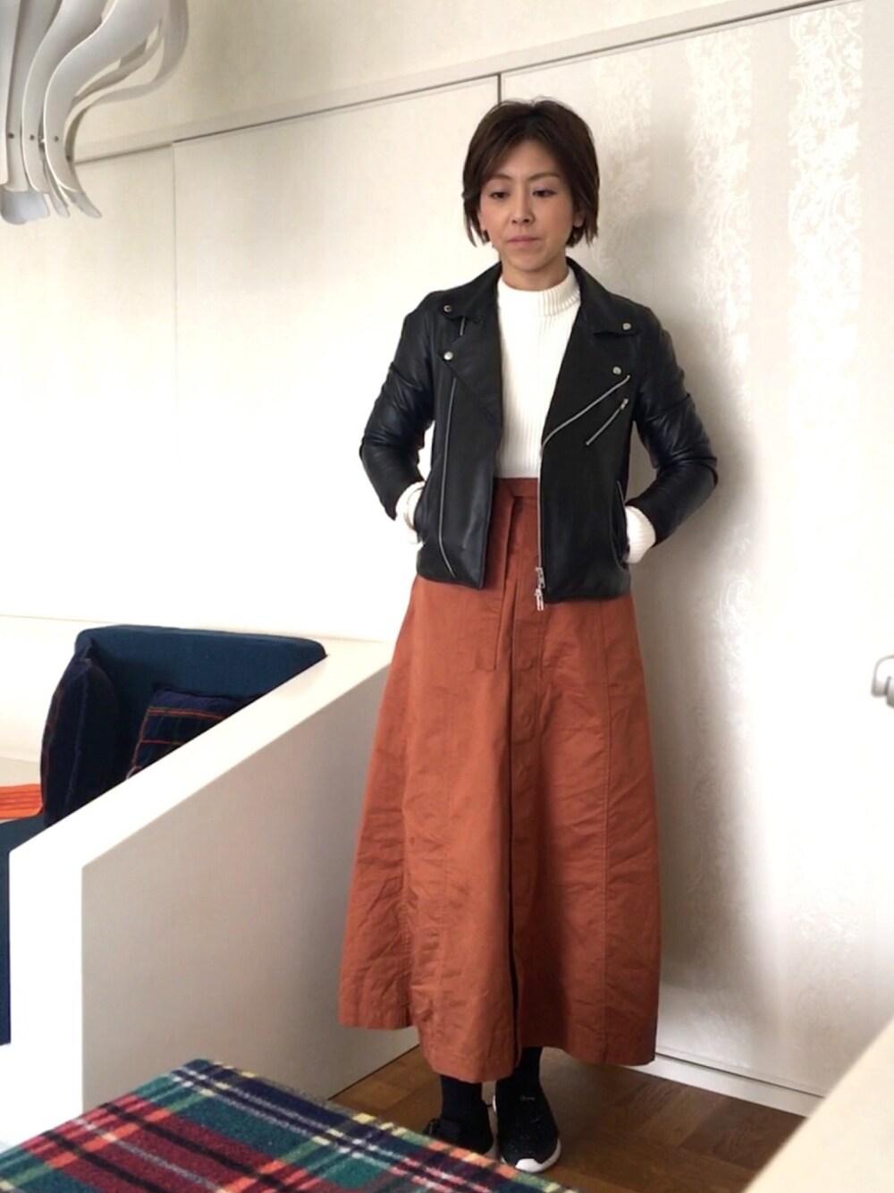 ホワイト系のニット/セーター、ブラック系のライダースジャケット、ブラウン系のスカートを着用したレディースの冬コーディネートの1枚目の写真
