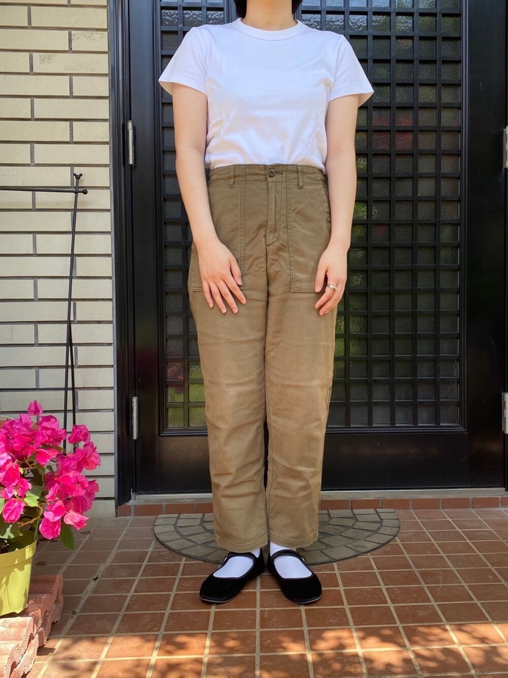 グリーン系のチノパンツ、ブラック系のバレエシューズ、ホワイト系のTシャツ/カットソーを着用したレディースの夏コーディネートの1枚目の写真