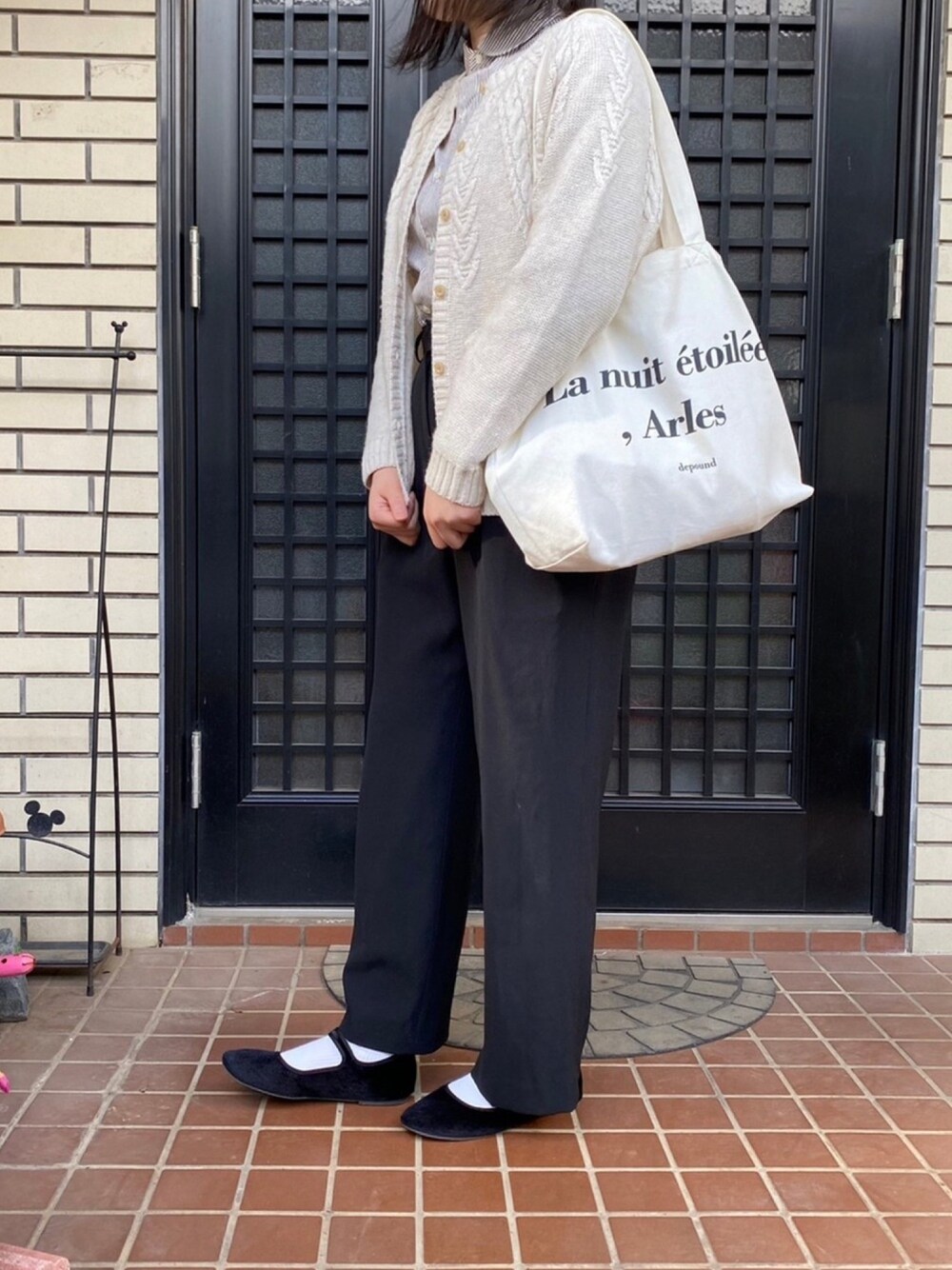 ブラック系のスラックス、ブラック系のバレエシューズ、ホワイト系のカーディガン/ボレロを着用したレディースの冬コーディネートの1枚目の写真