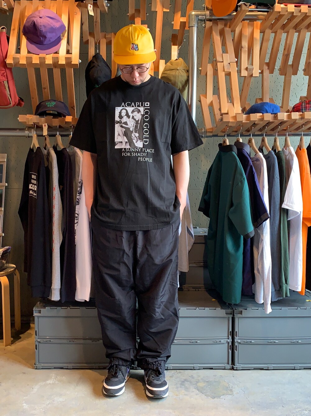 ブラック系のTシャツ/カットソー、ブラック系のその他パンツ、イエロー系のキャップを着用したメンズの春コーディネートの1枚目の写真