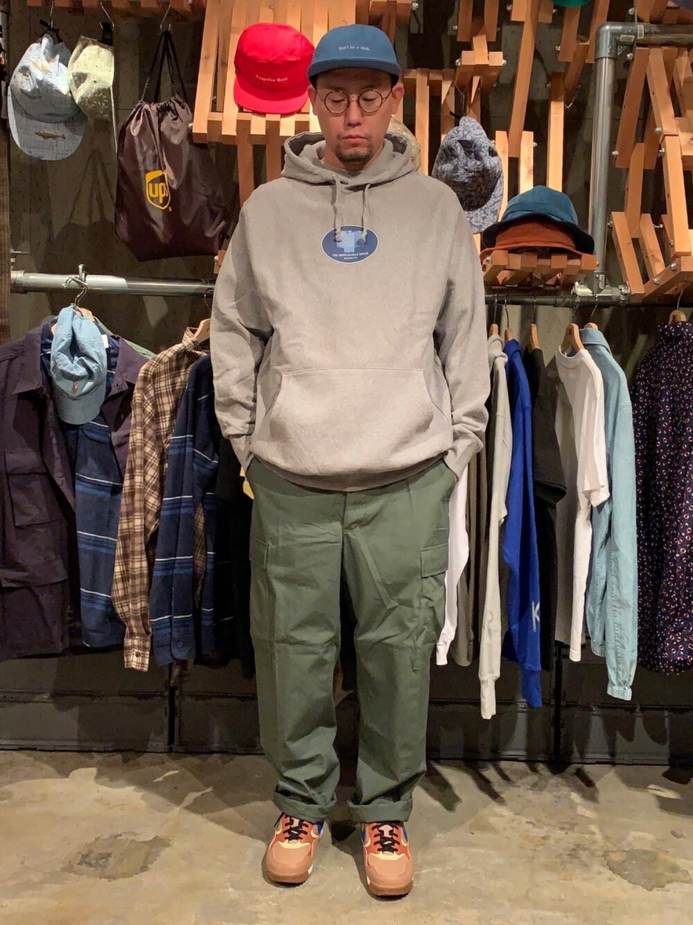 グレー系のパーカー、グリーン系のカーゴパンツ、ブルー系のキャップを着用したメンズの春コーディネートの1枚目の写真